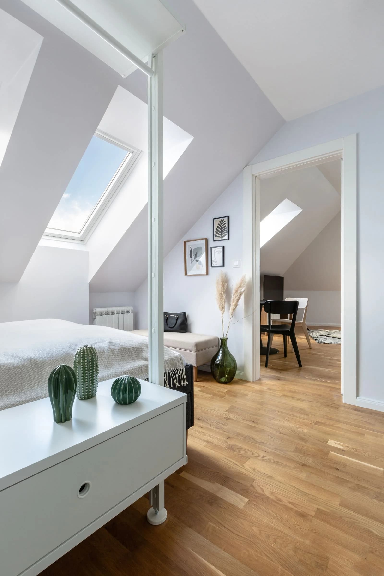 Light-filled loft bedroom with a pitched ceiling, roof window and oak floor — design inspiration