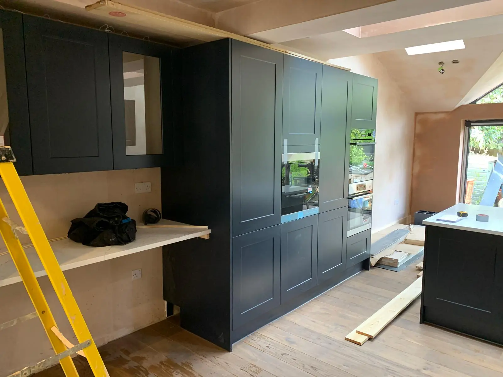 Dark kitchen cabinetry being installed